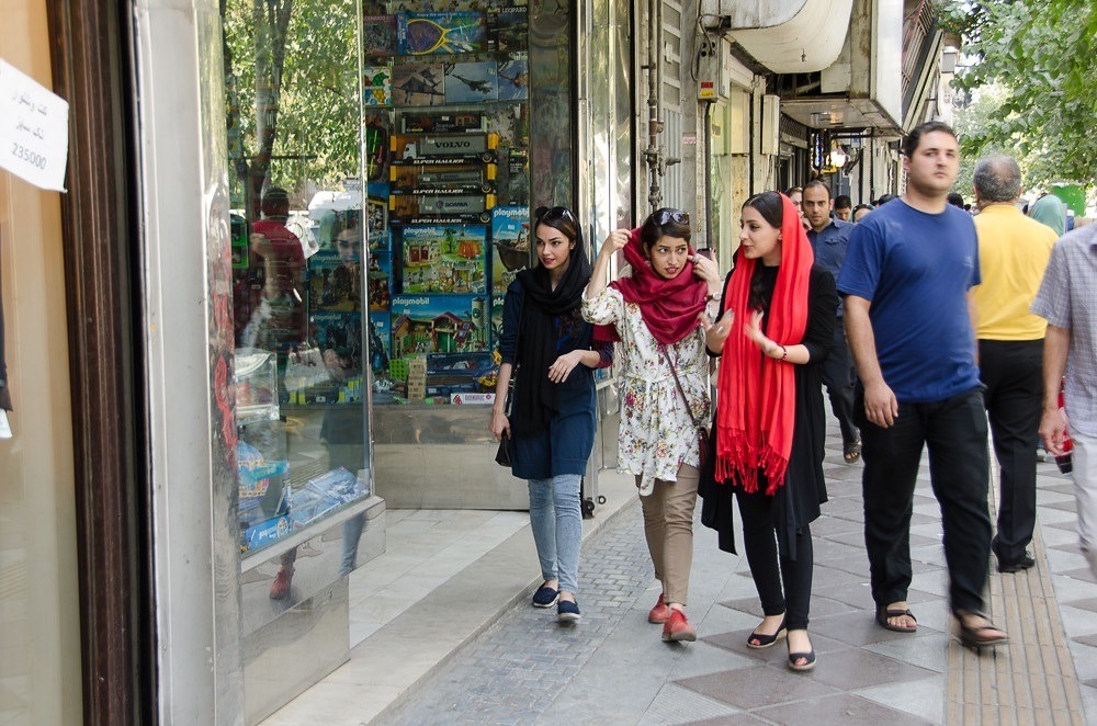 Photograph of three Iranian women walking on the street while talking