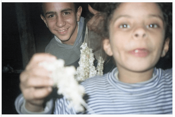 A girl and a teenage boy smile at the camera while holding candy