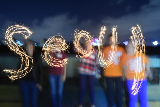 The word "Seoul" spelled out in sparklers with five people standing behind it