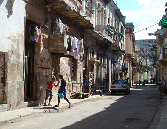 A street scene in Havana, Cuba, with two people and several cars.