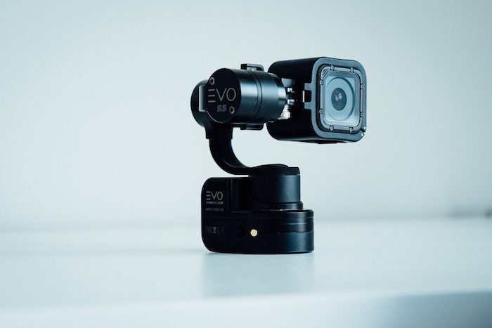 A small black video camera in front of a light blue background